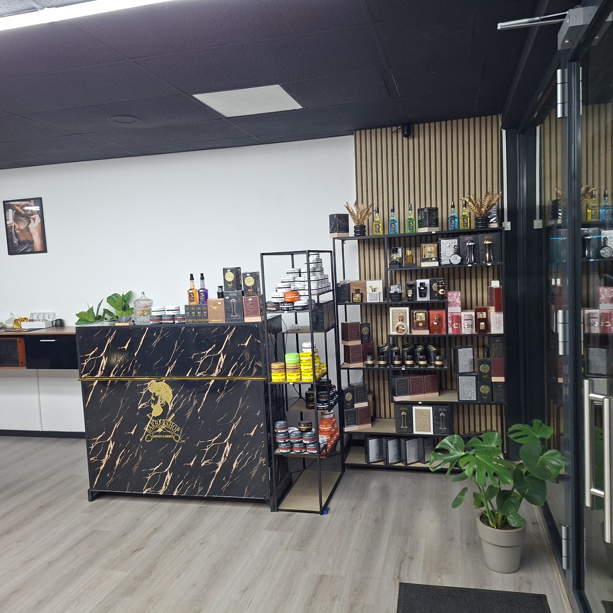 De balie in zwart-goud marmer met schappen vol haarproducten en een plant